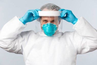 Covid-19, virüs, sağlık çalışanları ve aşı konsepti. Korunma ekipmanlarında uzman doktor. Coronavirus hastalığı üzerinde çalışırken yüz kalkanı ve solunum cihazı takın.