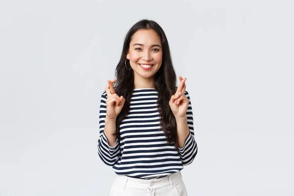 Estilo de vida, emoções das pessoas e conceito casual. Esperançoso animado bonito coreano feminino fazendo desejo com os dedos cruzados, sorrindo, antecipando notícias positivas, pleading dream come true — Fotografia de Stock