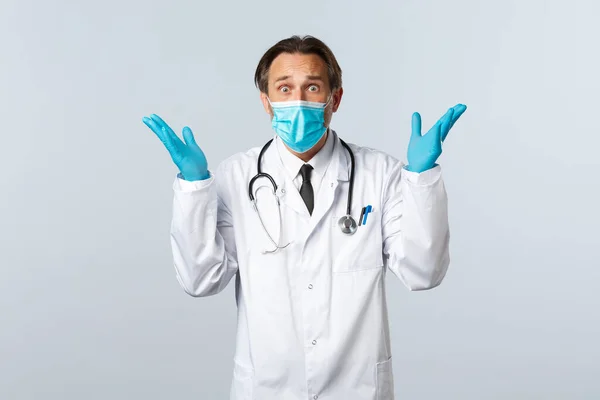 Covid-19, πρόληψη του ιού, εργαζόμενοι στον τομέα της υγείας και την έννοια του εμβολιασμού. Φοβισμένος γιατρός με ιατρική μάσκα και γάντια, ανήσυχη με τα χέρια ψηλά, πανικόβλητη με λευκό φόντο — Φωτογραφία Αρχείου