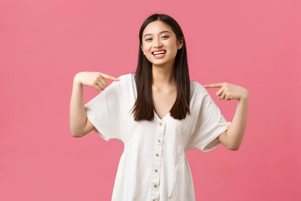 Beleza, emoções das pessoas e conceito de lazer e férias de verão. Entusiástico alegre bonito menina asiática em vestido branco, apontando para si mesma com cara de prazer, voluntária, juntando-se à empresa — Fotografia de Stock