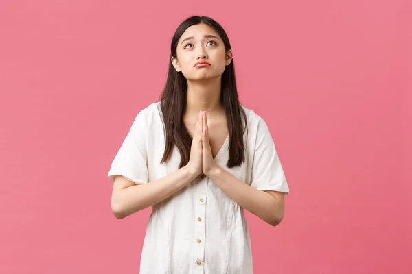 Beauté, émotions des gens et concept de loisirs d'été. Espérant triste fille asiatique mignonne en robe blanche, demandant de l'aide à Dieu, suppliant, priant et boudant bouleversé, debout fond rose — Photo