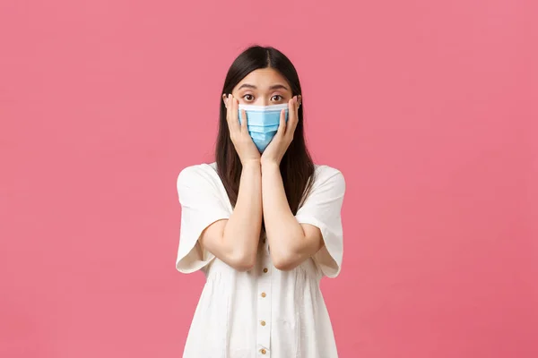 Covid-19, distanciamiento social, virus y concepto de estilo de vida. Mujer asiática conmocionada en vestido blanco y máscara médica, mirada preocupada y ansiosa por su propia salud durante el brote de coronavirus —  Fotos de Stock