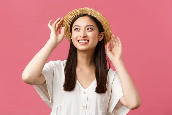 Beauté, émotions des gens et concept de loisirs et de vacances d'été. Élégante belle femme asiatique va faire du shopping ou marcher en plein air dans un nouveau chapeau de paille, souriant comme regarder loin sur fond rose — Photo