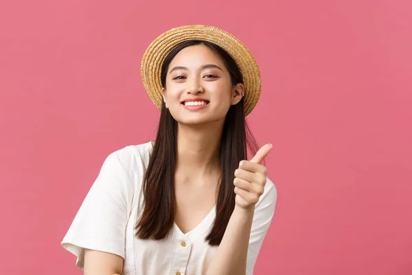 Belleza, emociones de la gente y el ocio y el concepto de vacaciones. Primer plano de satisfecho lindo asiático mujer cliente sugerir impresionante tienda con ropa de verano, mostrar los pulgares hacia arriba, usar sombrero de paja —  Fotos de Stock