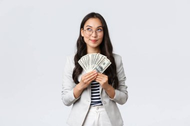İş, finans ve istihdam, girişimci ve para kavramı. Hayalperest iş kadını nereye tatile gideceğini düşünüyor ve nasıl para kazanacağını düşünüyor, nakit tutuyor ve düşünceli bir iş kadını arıyor.
