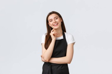 Küçük işletmeler, çalışanlar ve kahve dükkanı konsepti. Siyah önlüklü neşeli, sevimli tezgahtar kahkaha atıyor, baristayla dostça sohbet ediyor. Markette mola veren kadın, beyaz arka plan.