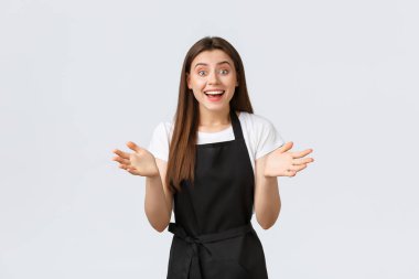 Küçük işletmeler, çalışanlar ve kahve dükkanı konsepti. Rahatlamış neşeli kahveci iyi iş çıkarmış. Siyah önlüklü, gülümseyen satıcı kadın alkışlıyor ve alkışlıyor.