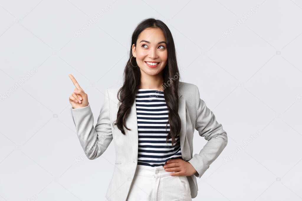 Business, finance and employment, female successful entrepreneurs concept. Cheerful successful businesswoman in white suit pointing fingers upper left corner, showing advertisement