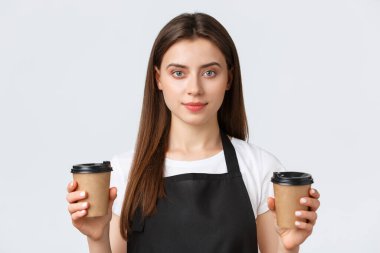 Çalışanlar, iş, küçük işletme ve kahve dükkanı konsepti. Gülümseyen arkadaş canlısı bayan baristanın yakın çekimi, kafe çalışanı müşteriye iki fincan kahve ısmarlıyor.