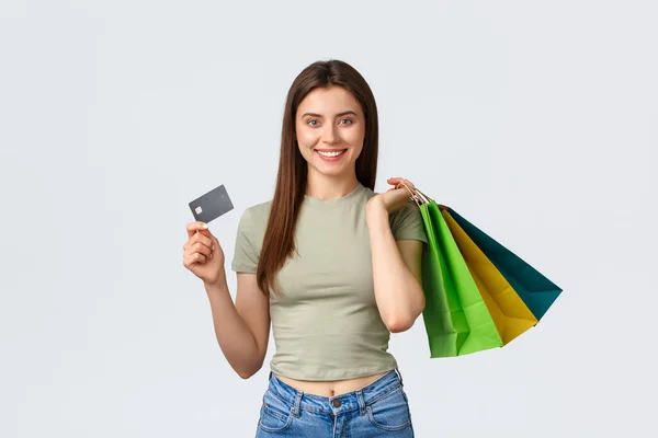 Shopping center, estilo de vida e conceito de moda. Jovem elegante alegre comprando roupas novas, sacos de espera e cartão de crédito, sorrindo para a câmera como publicidade verão descontos especiais — Fotografia de Stock