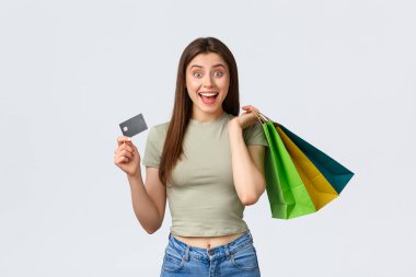 Alışveriş merkezi, yaşam tarzı ve moda konsepti. Neşeli, şık genç bir kadın yeni kıyafetler alıyor, el çantaları ve kredi kartları alıyor, kameraya gülümsüyor ve yaz indirimleri yapıyor.