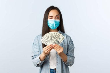 Sosyal mesafeli yaşam tarzı, covid-19 pandemik iş ve heyecan konsepti. Tıbbi maske takan başarılı kadın serbest yazar, iş arama sitesine kaydolmayı teşvik ediyor, para gösteriyor.