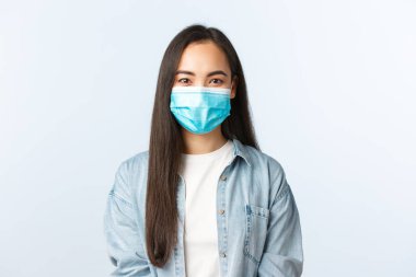 Sosyal mesafeli yaşam tarzı, covid-19 salgını günlük yaşam ve eğlence kavramı. Tıbbi maskeli neşeli Asyalı kız Coronavirus salgını sırasında kendini karantinada tutuyor.