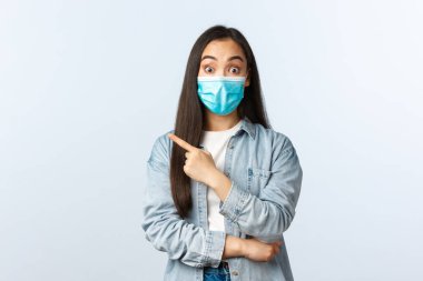 Sosyal mesafeli yaşam tarzı, covid-19 salgını günlük yaşam ve eğlence kavramı. Heyecanlı, yakışıklı, tıbbi maskeli bir Asyalı kız mağazadaki yeni ürünler hakkında konuşuyor.