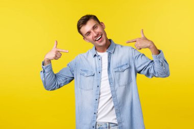 Portrait of happy handsome blond male student pointing at himself and smiling joyfully. Guy show-off, bragging over personal achievement, being excited as got job or promotion, yellow background clipart