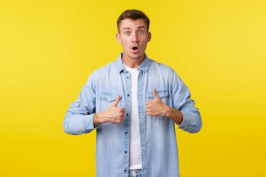 Etkilenmiş genç adam harika kurslara ya da etkinliklere katıldıktan sonra baş parmağını kaldırdı. Yakışıklı, heyecanlı adam, inanılmaz bir tanıtım teklifi, harika bir fikir, sarı arka planda durmak.