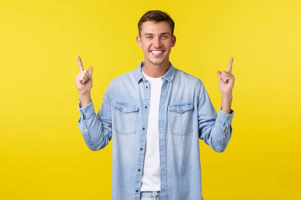 Gelukkig knappe volwassen man met perfecte witte glimlach, wijzende vingers omhoog, demonstreren banner, reclame en het aanbevelen van te kopen product, speciale zomer korting, staande gele achtergrond — Stockfoto