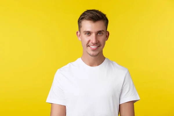 Lifestyle, zomer en mensen emoties concept. Close-up portret van knappe jongeman in casual wit t-shirt, glimlachen op camera blij, staande gele achtergrond — Stockfoto