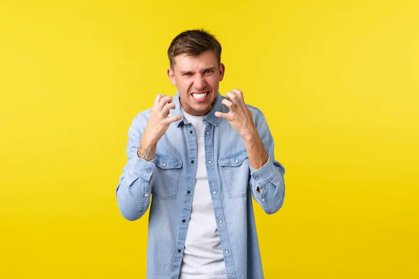 Lifestyle, people emotions and summer leisure concept. Angry and pissed-off annoyed caucasian man, clench fists hateful and grimacing aggressive, losing temper feeling irritated, yellow background — Photo