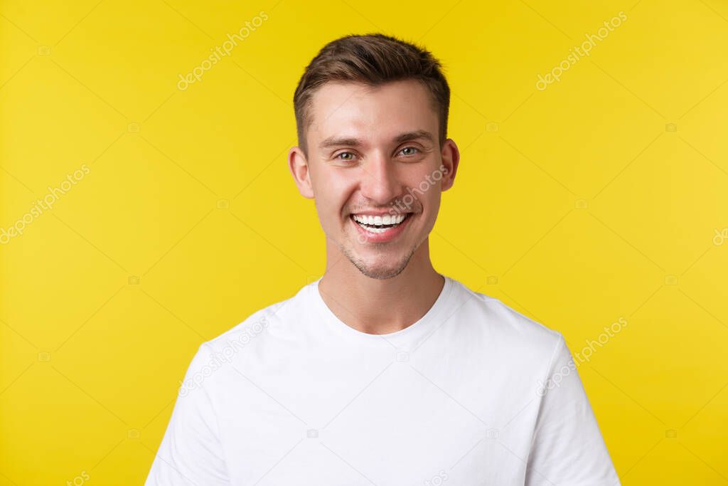 Lifestyle, summer and people emotions concept. Enthusiastic handsome male model with happy smile and white teeth, standing in casual t-shirt over yellow background satisfied
