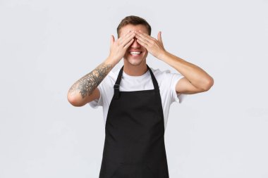 Çalışanlar, bakkallar ve kahve dükkanı konsepti. Heyecanlı, mutlu barista, garson ya da mağaza çalışanı. Gözleri kapalı, neşeli bir şekilde gülümsüyor, sürpriz bekliyor, beyaz arka planda duruyor.