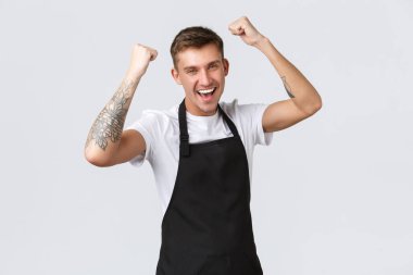 Çalışanlar, bakkallar ve kahve dükkanı konsepti. Mutlu yakışıklı barista, erkek kafe çalışanı ya da garson, açılışı kutluyor, yumruk tokuşturuyor ve evet diyor, zafer kazanıyor, şampiyon gibi hissediyor.