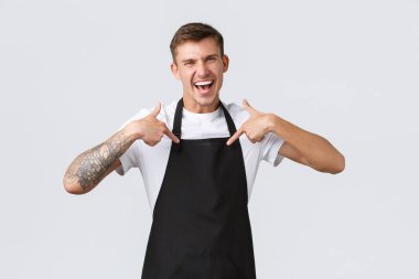 Küçük işletme sahipleri, kahve dükkanı ve personel konsepti. Hevesli, mutlu, yakışıklı barista tanıtımı kontrol etmeye davet ediyor, parmakla işaret ediyor ve gülüyor, büyük reklam indirimleri ilan ediyor.