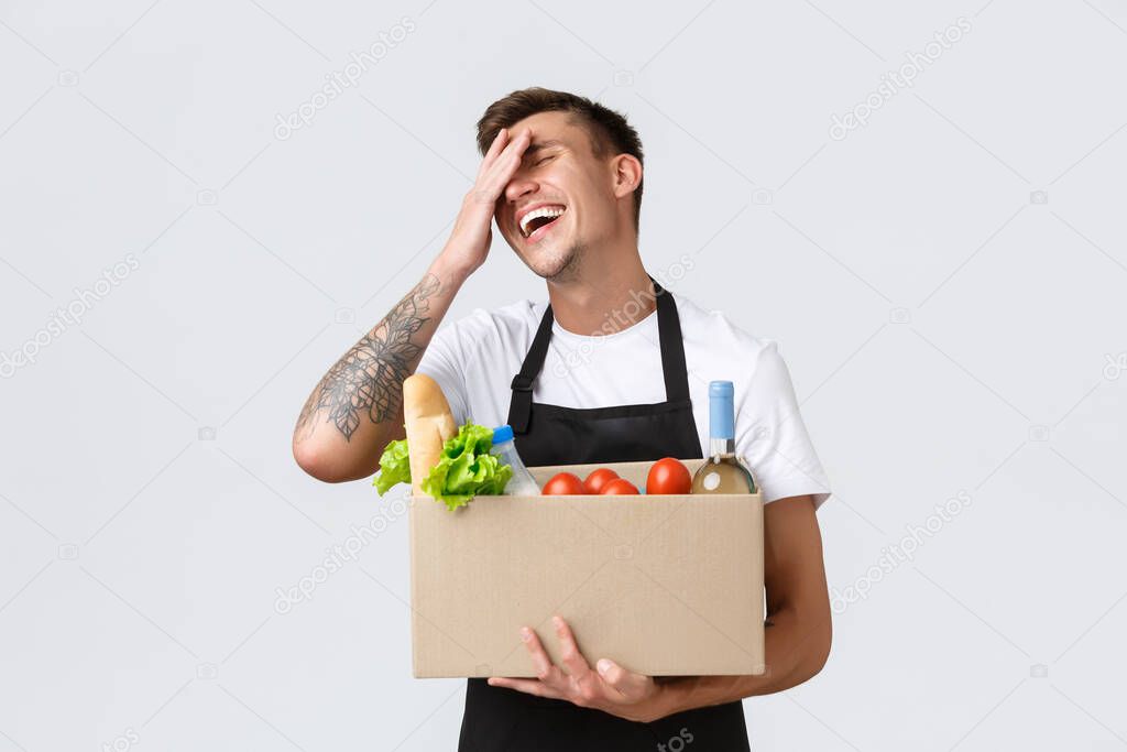 Retail, grocery shopping and delivery concept. Silly cheerful salesman in store packing order for couriers, holding box with food, selling groceries, laughing and smiling upbeat, white background