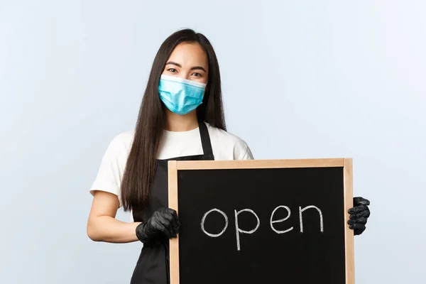 Småföretag, covid-19 pandemi, förebygga virus och anställda koncept. Le söt asiatisk kvinnlig anställd, café eller butik arbetare som håller öppen skylt, bjuda in besökare — Stockfoto