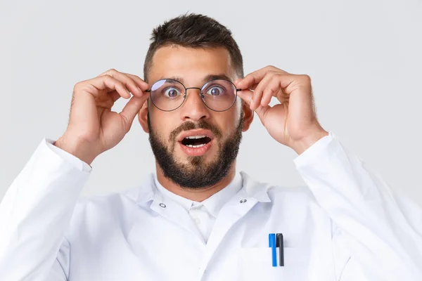 Healthcare workers, coronavirus, covid-19 pandemic and insurance concept. Close-up of excited and impressed hispanic doctor in white coat, put on glasses gasping and staring astonished — Stock Photo, Image