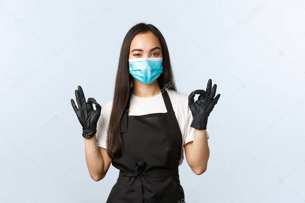 Covid-19, social distancing, small coffee shop business and preventing virus concept. Employee have all under control, guarantee quality, show okay sign, wearing medical mask and gloves
