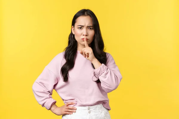 Gente emociones, estilo de vida y concepto de moda. enojado disgustado joven asiático mujer decir estar tranquilo, callar con decepcionado cara, silencio con el dedo presionado a los labios insatisfecho, amarillo fondo — Foto de Stock