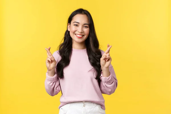 As pessoas emoções, estilo de vida e conceito de moda. Esperançoso e otimista bonito asiático menina ter alta esperança, cruz dedos boa sorte e sorrindo, fazendo desejo, de pé fundo amarelo — Fotografia de Stock