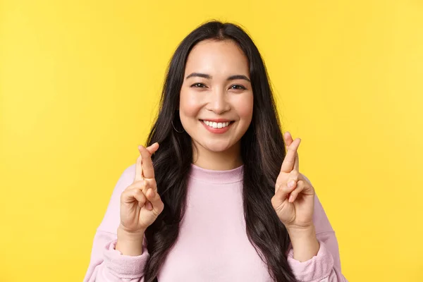 Pessoas emoções, lazer estilo de vida e conceito de beleza. Excitada mulher asiática sorrindo amplamente, cruz dedos boa sorte, fazendo desejo sonhador, implorando ou ter fé, ficar fundo amarelo — Fotografia de Stock