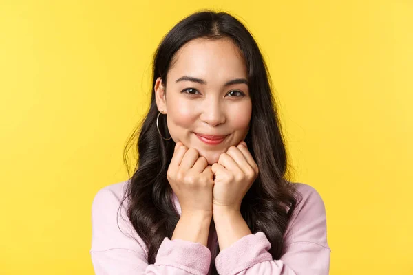 Pessoas emoções, lazer estilo de vida e conceito de beleza. Linda mulher asiática sorrindo para a câmera e olhando simpatia, carinho, sentindo alegria e amor, loja de publicidade, stand yellow background — Fotografia de Stock