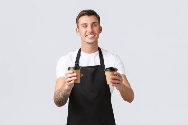 Küçük işletme, kafe, kafe ve restoran konsepti. Yakışıklı, karizmatik barista, garsonun paket kahveyi kağıt bardaklarda dağıtması, misafirler için sipariş hazırlaması, beyaz arka planda içki satması.