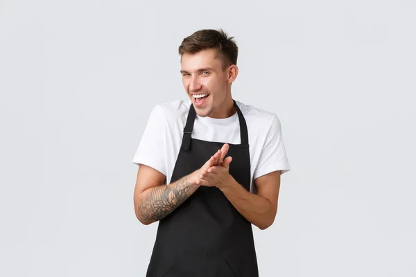 Small business owners, coffee shop and staff concept. Devious and smart funny barista in black apron, cafe worker rubbing hands as feeling relish or satisfaction from accomplished plan, grinning sly — Stock Photo, Image