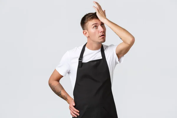 Medewerkers, kruidenierszaken en coffeeshop concept. Vervelende en lastige barista, cafe manager of ober, punch voorhoofd, facepalm en ogen roll geïrriteerd, staande witte achtergrond — Stockfoto