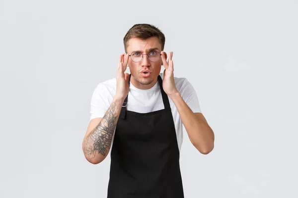 Kleine winkeliers, café en restaurant medewerkers concept. Geïntrigeerd en onzeker knappe ober, barista die beter kijkt, bril op en staar camera, witte achtergrond — Stockfoto