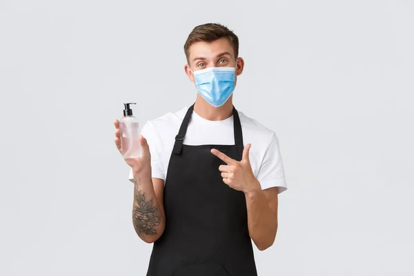 Coronavirus, social distancing in cafes and restaurants, business during pandemic concept. Waiter or barista explain importance of wearing mask and using hand sanitizer to disinfect — Stock Photo, Image