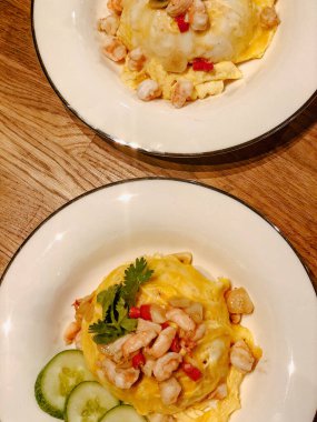 Lava omletini üzerine karides koyup beyaz yuvarlak bir tabakta pilav ile servis et. Lezzetli görünüyor.