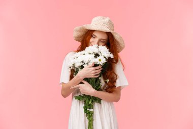 Romantizm, aşk ve ilişki kavramı. Romantik rüya gibi, çekici kızıl saçlı kız çiçekleri kokluyor, gözlerini kapatıyor ve güzel bir bukete sarılıyor, pembe arka planda duruyor.