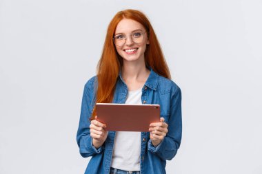 Eğitim, insanlar ve takım çalışması konsepti. Neşeli, güzel, kızıl saçlı, milenyum çalışanı, projeyi takıma tanıtan, dijital tablet taşıyan, gözlük takan, kameraya gülümseyen.
