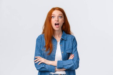 Omg, olamaz, inanılmaz. Etkilenmiş ve şaşırmış, meraklı kızıl saçlı kız şaşkınlıktan çenesini düşürüyor, konuşmasını kaybediyor, şaşkın şaşkın bakıyor, hayret içinde duruyor, müthiş bir haber buldu, beyaz arka plan