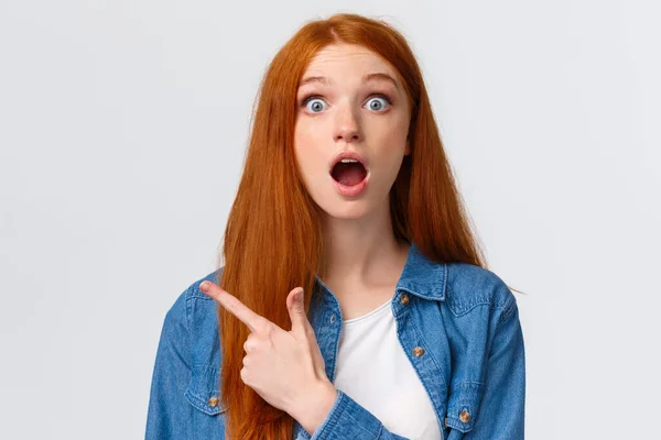 Close-up portret onder de indruk geschud en sprakeloos mooi roodharige vrouwelijke student, tiener wijzen linksboven hoek drop kaak, bespreken verbazingwekkende banner, product advertentie, witte achtergrond — Stockfoto