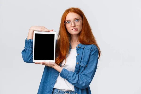 Cant resistere alla tentazione, aggiungere al carrello ora. Allettante e curioso bell'aspetto eccitato rossa donna in occhiali, mordente desiderio labbro acquistare qualcosa online, mostrando schermo tablet digitale, sfondo bianco — Foto Stock