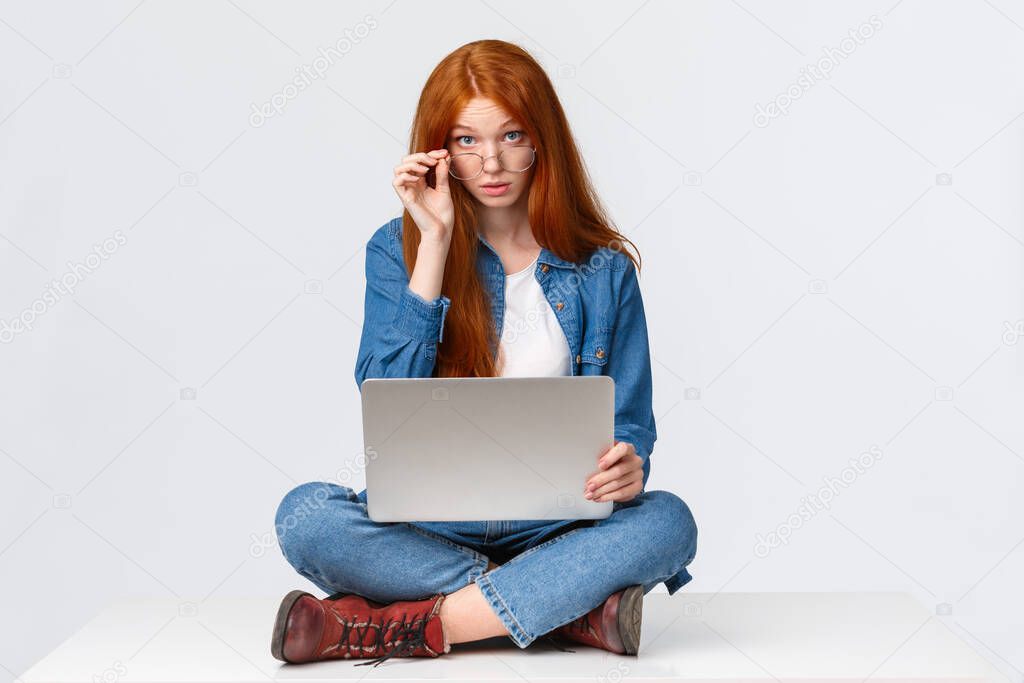 Excuse me what, I am busy. Questioned redhead female student interrupted during preparing project, searching material for class in internet, look curious camera, sitting on floor with laptop