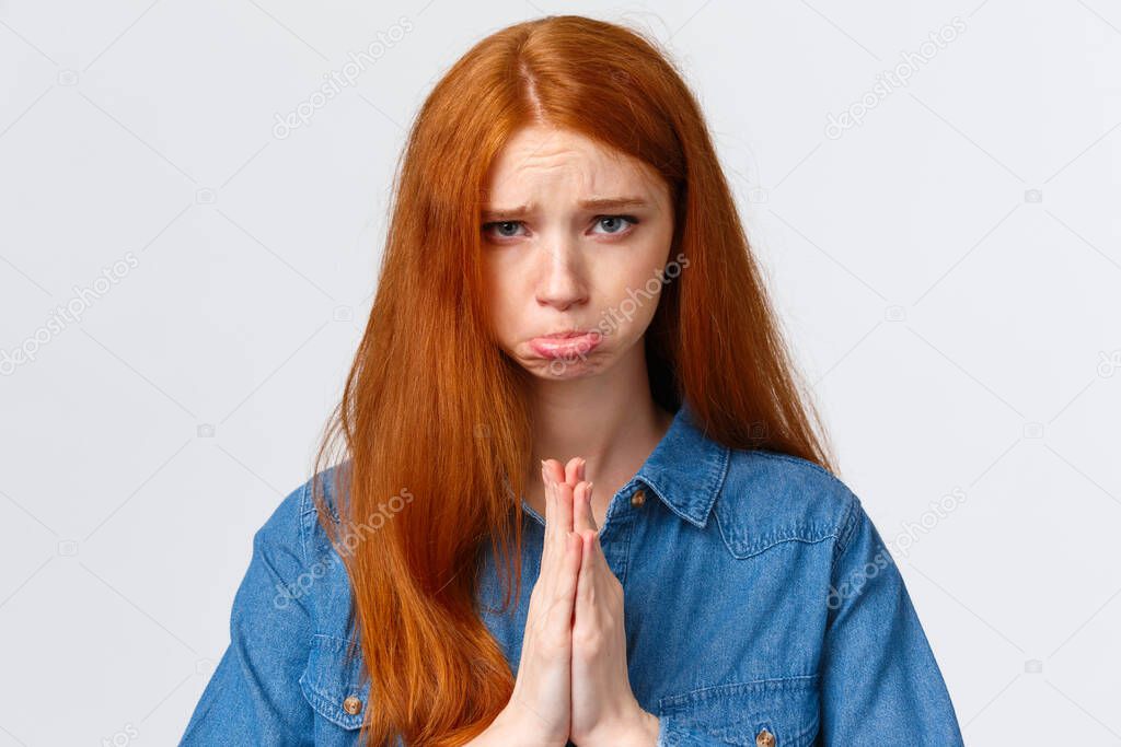 Pretty please. Close-up portrait sad, sulking cute redhead girl feeling guilty begging apology, pouting and frowning hopeful look camera, press hands together in pray, pleading over white background