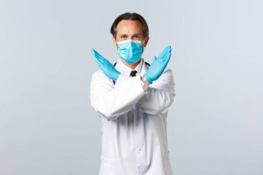 Covid-19, virüsü önleme, sağlık çalışanları ve aşı konsepti. Coronavirus 'la savaşan kararlı bir doktor ne yapmayacağını söyler, kollarını kavuşturur ya da yasaklama hareketi yapar.