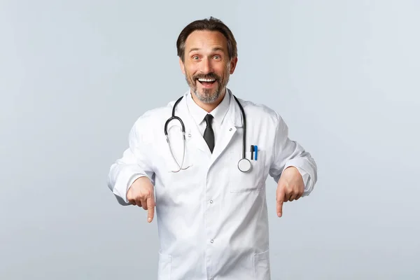 Covid-19, Coronavirus-Ausbruch, Gesundheitspersonal und Pandemiekonzept. Glücklich lächelnder Arzt in weißem Mantel, der zum Klicken einlädt. Therapeut zeigt Weg zur Werbung auf und lädt Patienten ein — Stockfoto